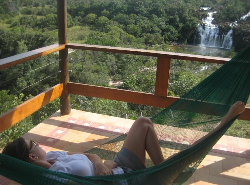 
a man laying in a hammock on top of a beach at Pousada Cachoeira Poço Encantado in Alto Paraíso de Goiás
